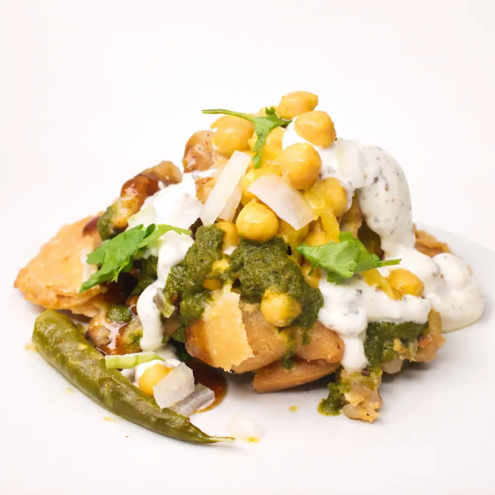 Crushed samosa mixed with chickpeas, chutneys, and spices